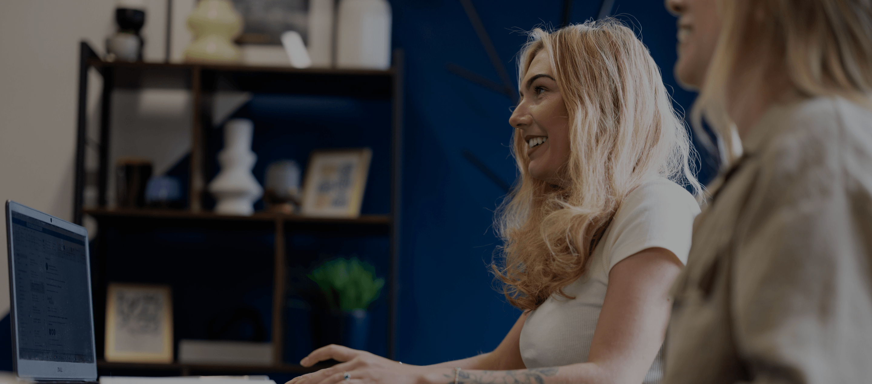 Two women in a blue office, one in focus. 